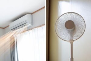 A wall-mounted air conditioner blowing cool air, next to a standing fan.